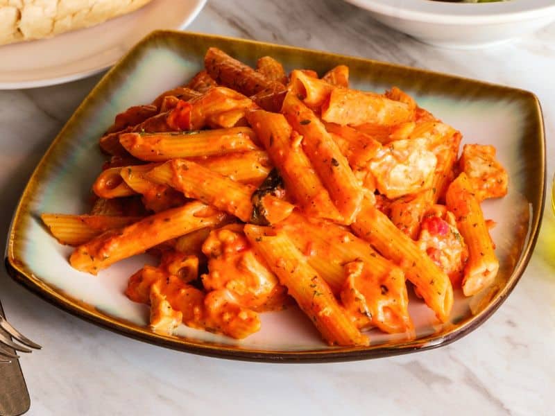 Indulge in the richness of Penne alla Vodka accompanied by succulent chicken, from a captivating top perspective.