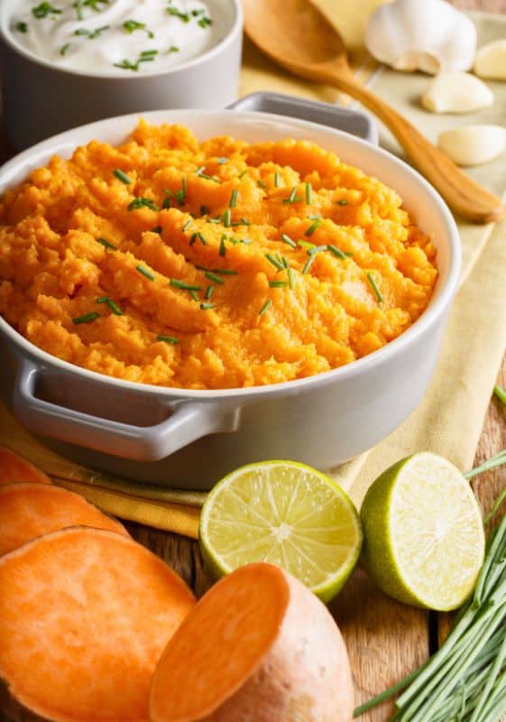 Top view of a bowl full of creamy mashed sweet potatoes, sprinkled with chopped chives for an extra burst of flavor. 
