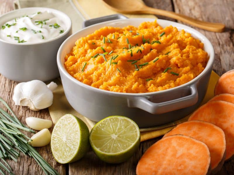 Top view of a bowl full of creamy mashed sweet potatoes, sprinkled with chopped chives for an extra burst of flavor.