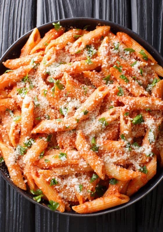 Budget-friendly and easy to prepare Penne Vodka, garnished with chopped basil and parmesan cheese.