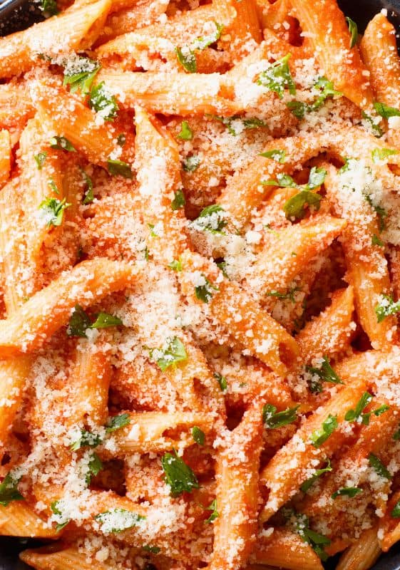 Close-up of Penne alla Vodka, beautifully adorned with fresh basil and a generous sprinkle of parmesan.