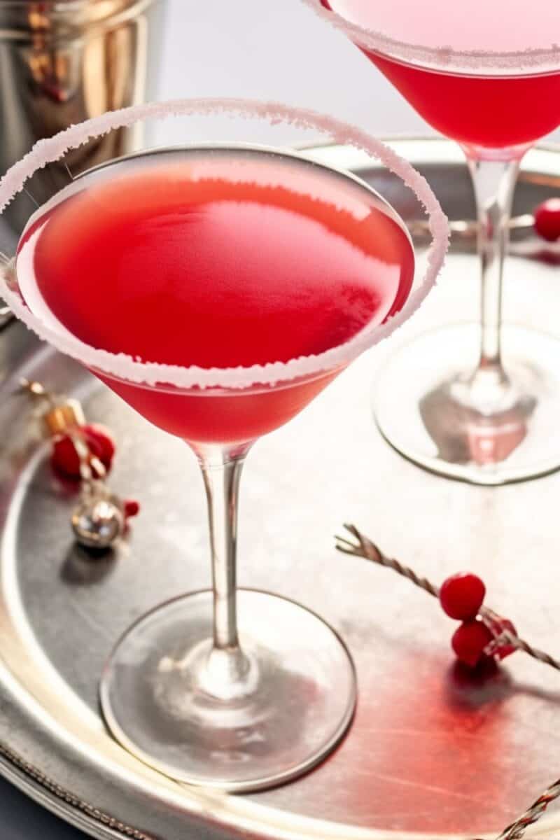 Overhead view of a Candy Cane Cocktail in a glass rimmed with crushed candy canes, garnished with a whole candy cane, set on a festive backdrop.
