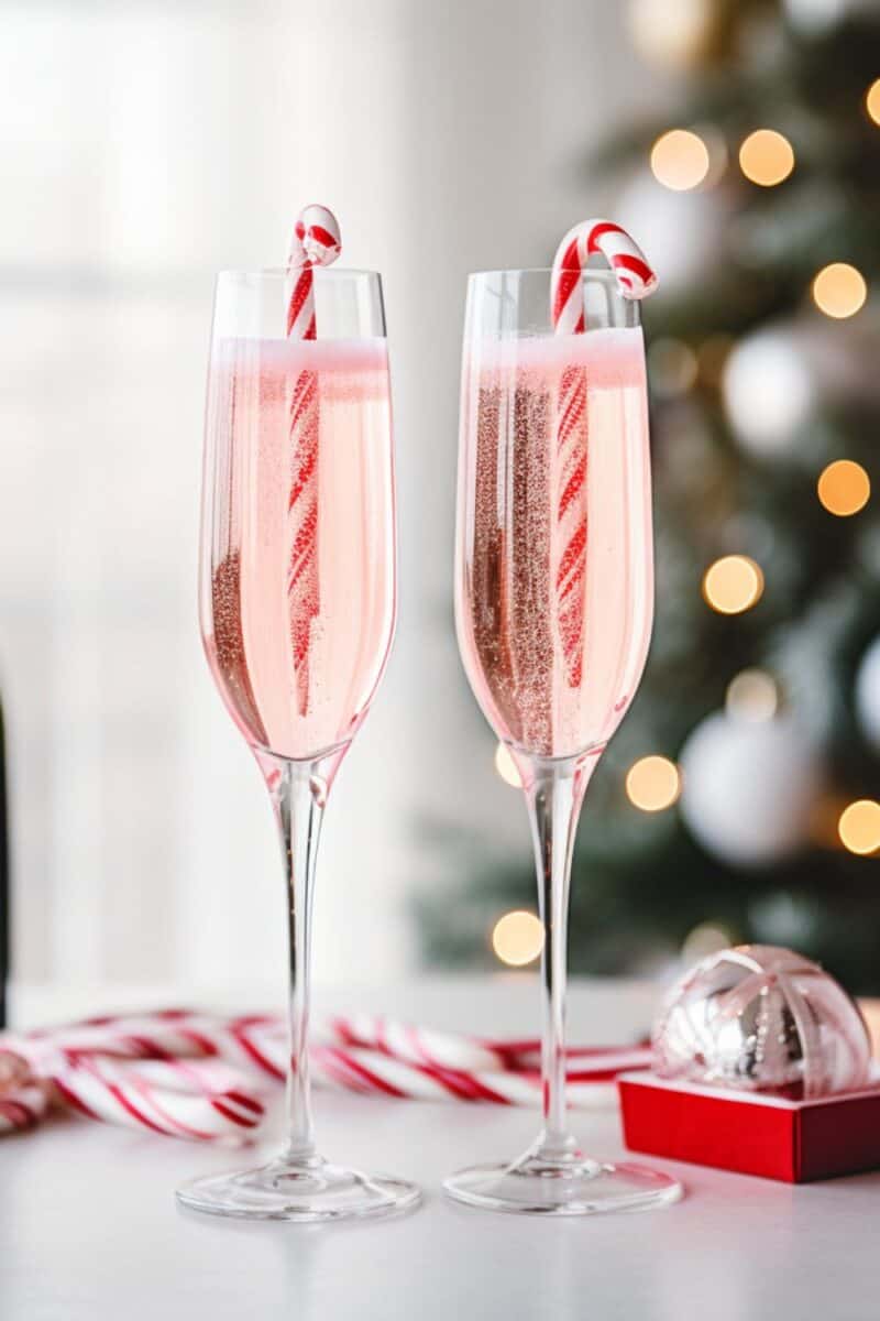 Pair of holiday cocktails featuring Peppermint Bark Mimosas, garnished with candy canes, perfect for a holiday party.