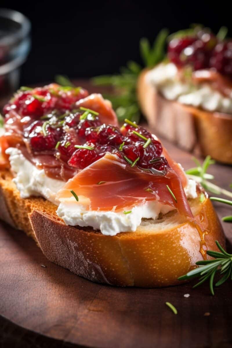 Zoomed-in detail of the texture contrast between the crispy baguette, creamy goat cheese, and the toppings of cranberry and prosciutto.