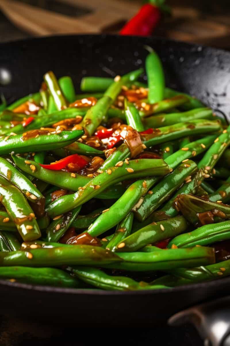 Freshly cooked Stir-Fried Green Beans, glistening with sauce and seasoned with aromatic spices, arranged neatly on a round plate against a minimalist background.
