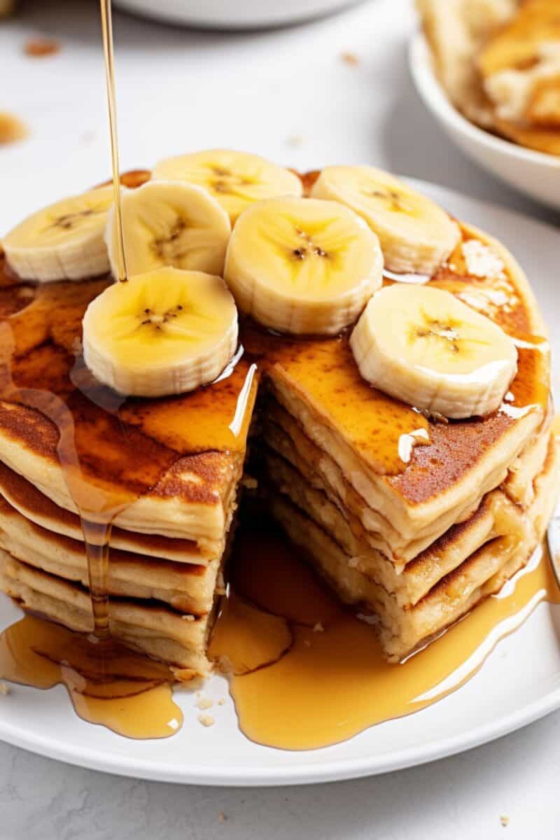 Freshly made banana pancakes stacked on a plate, topped with sliced bananas and a drizzle of maple syrup, perfect for a homemade breakfast