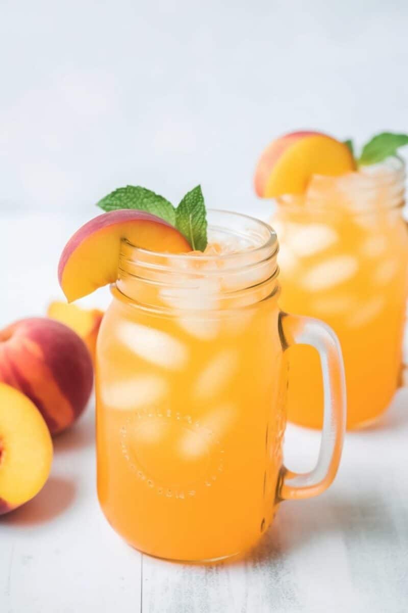 Overhead view of two mason jars filled with peach homemade lemonade, placed side by side