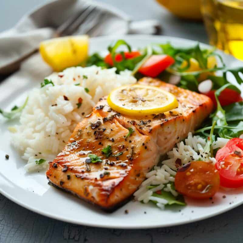 A plate of Pan Seared Salmon, golden and crisp on the outside, served over fluffy cilantro rice with a fresh side salad of mixed greens.