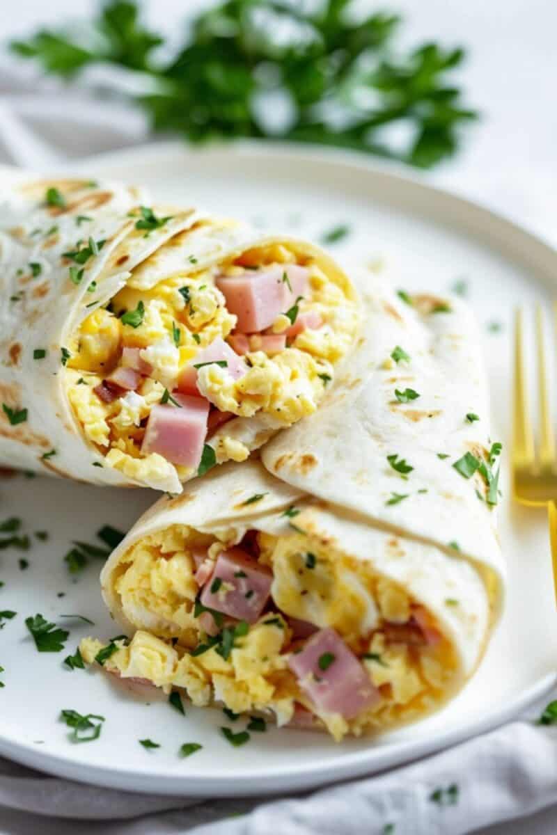 A Scrambled Egg and Cheese Tortilla Roll, featuring fluffy eggs, ham and melted cheese rolled up in a crisp tortilla, served as a delicious and convenient breakfast option.