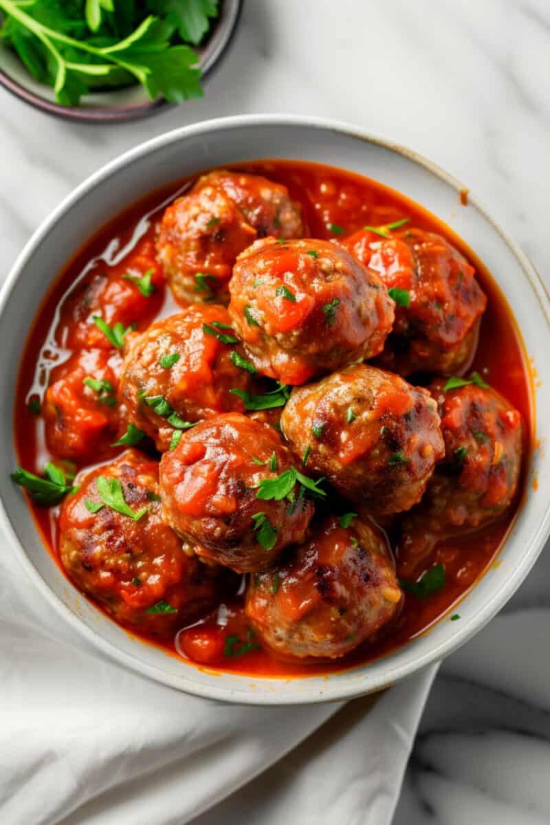Juicy Italian meatballs covered in a thick tomato sauce with a sprinkle of grated Parmesan cheese, served in a rustic ceramic dish.