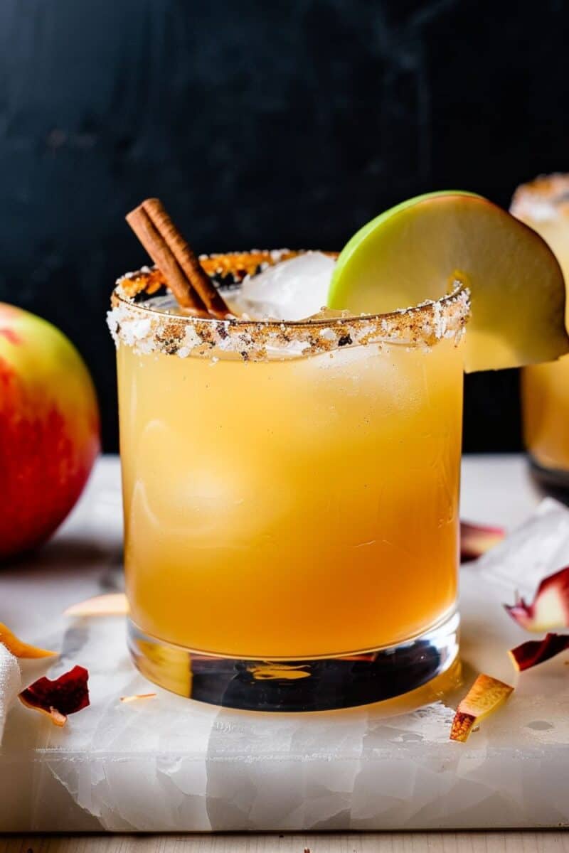 A chilled glass of Tequila Apple Cider Cocktail, garnished with a fresh apple slice and a cinnamon stick, offering a refreshing taste of autumn.