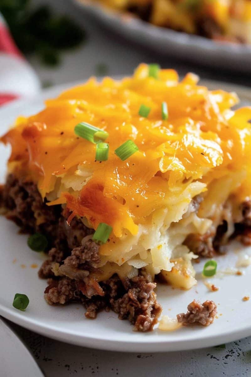 A single serving of ground beef hash brown casserole on a white plate.