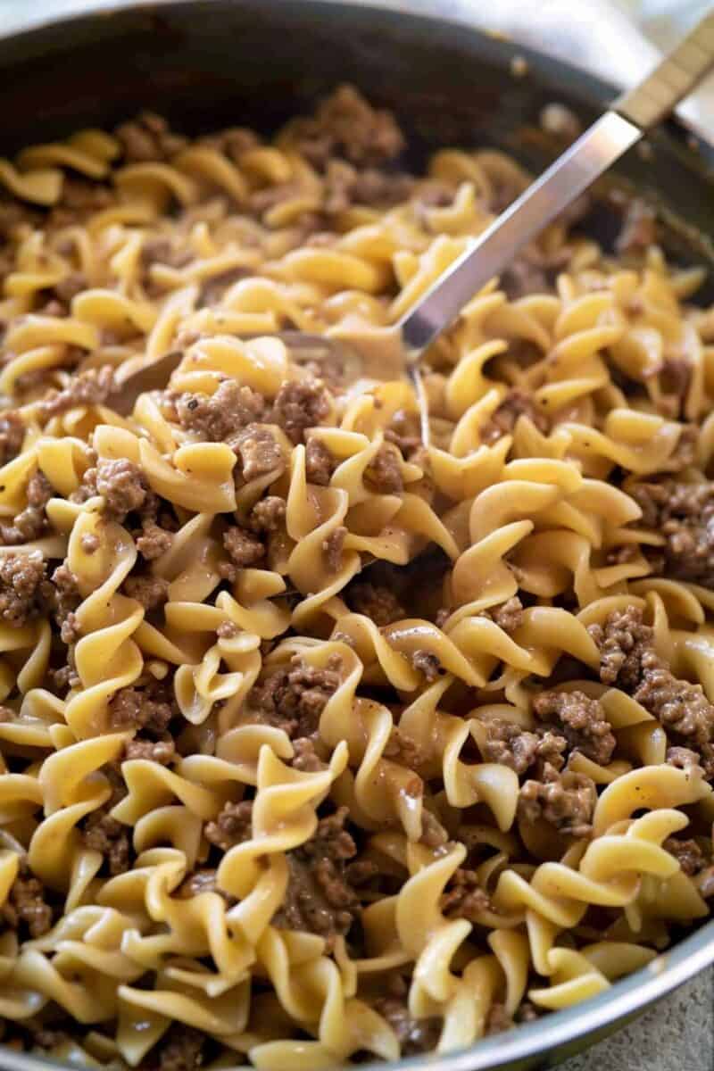 Ground beef stroganoff with spoon held mid air over pan.