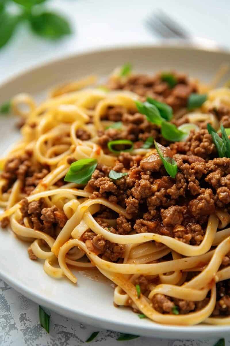 Mongolian noodles with ground beef in white bowl.