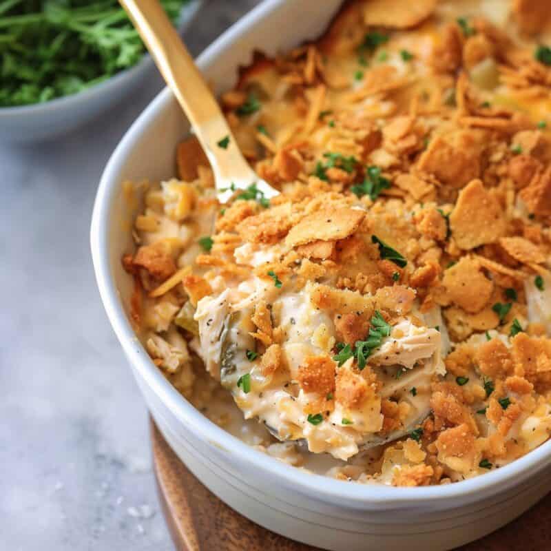 A golden, bubbling Million Dollar Chicken Casserole fresh from the oven, featuring a creamy, savory filling of tender chicken mixed with cream cheese, cottage cheese, and sour cream, seasoned with garlic and onion powder, all topped with a crispy, buttery layer of crushed Ritz crackers. The dish is presented in a white baking dish, with steam rising from the surface, indicating its piping hot readiness to be served.