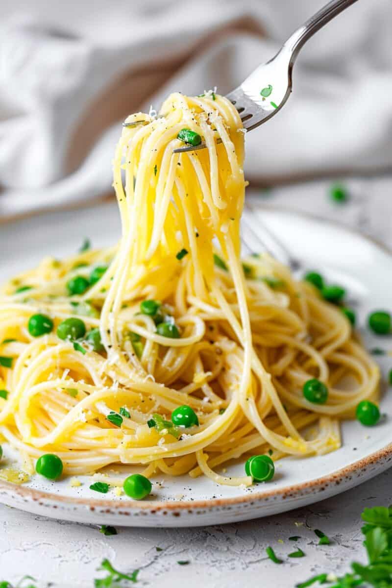 A plate of spaghetti twirled on a fork above a dish garnished with green peas, grated cheese, and parsley, embodying a simple, fresh spring pasta meal.