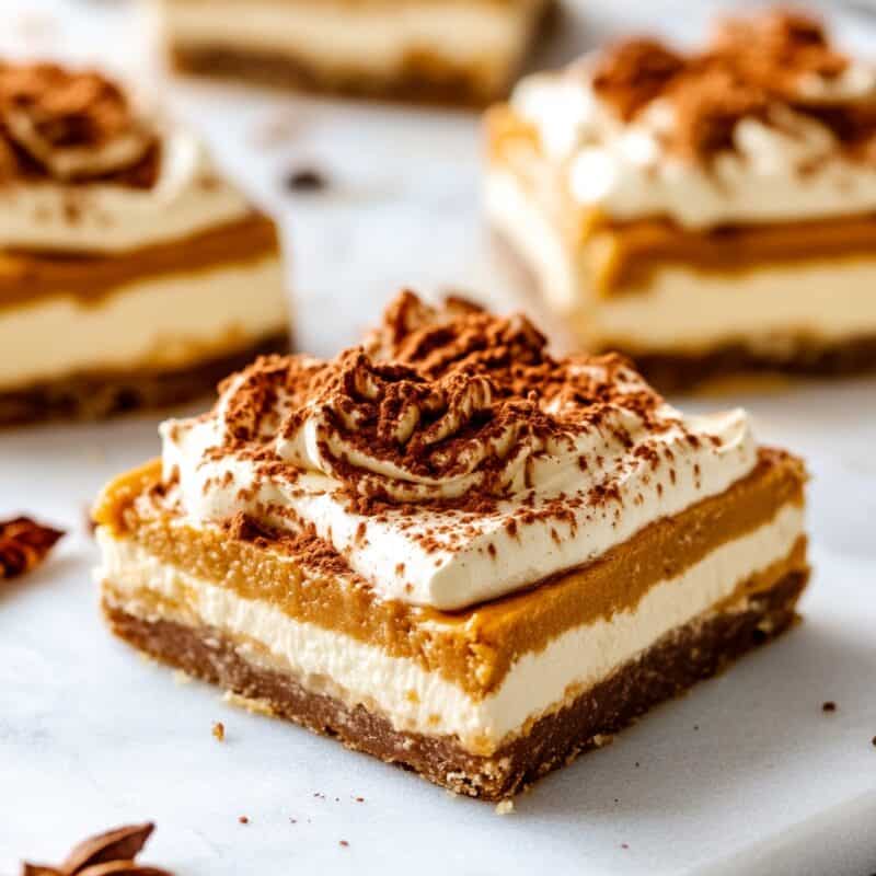 Delicious layered square of creamy, low-carb dessert topped with whipped cream and cocoa powder, perfect for Keto Thanksgiving Desserts.