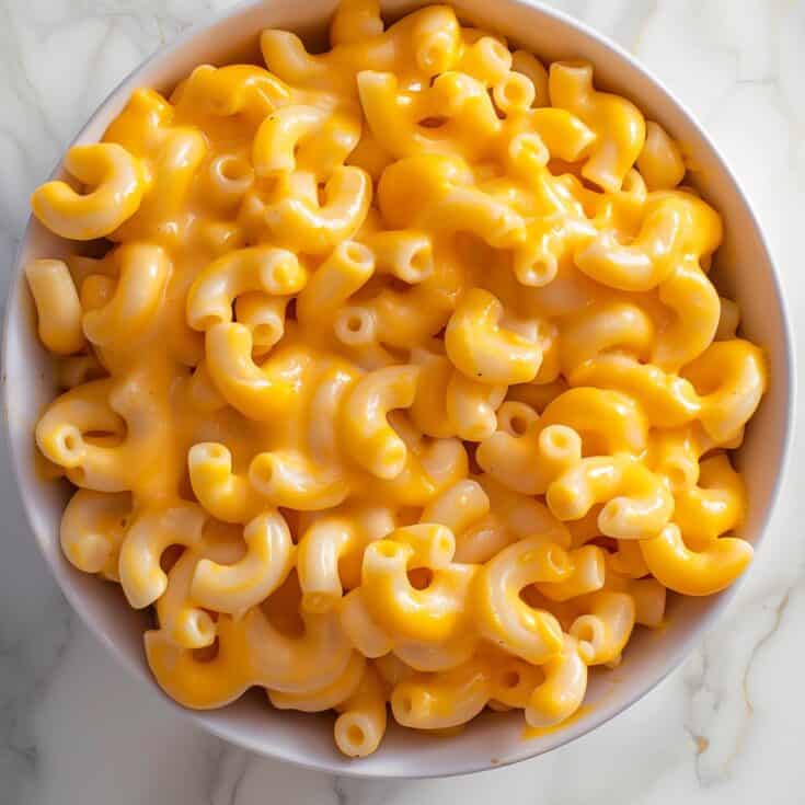 An overhead view of a bowl of Pumpkin Mac and Cheese, showcasing the perfectly cooked elbow macaroni generously coated in a creamy, pumpkin-infused cheese sauce.