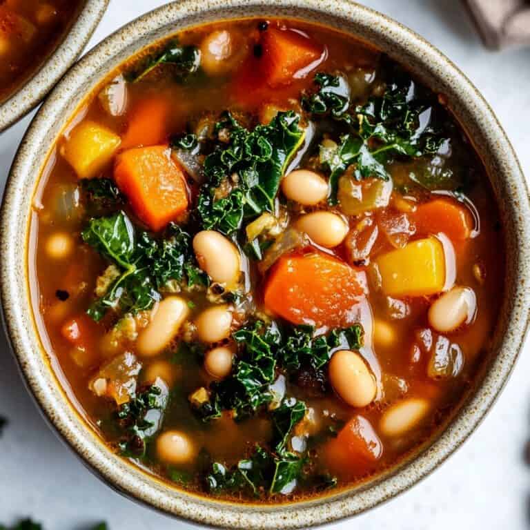 White Bean and Kale Soup: A hearty white bean and kale soup featuring tender white beans, chunks of carrots, and vibrant green kale in a flavorful broth. The rustic presentation offers a comforting blend of colors and textures.