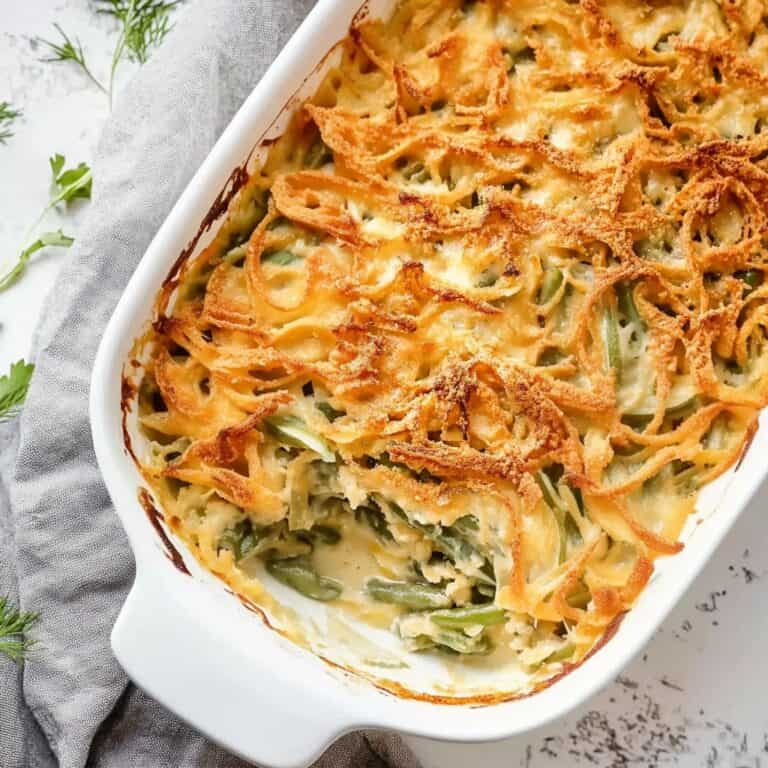 Golden-brown, crispy-topped Green Bean Casserole in a white baking dish. A comforting holiday classic with a creamy mushroom base and crispy fried onions, perfect for Thanksgiving or any family gathering.