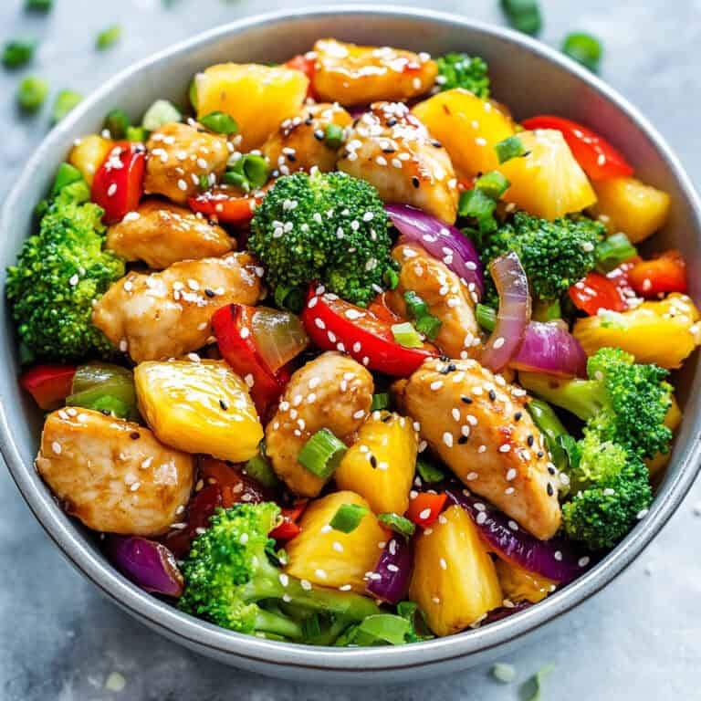 Close-up of Pineapple Chicken bowl, highlighting the vibrant mix of textures and flavors with sesame-topped chicken and bright vegetables in a rich sauce.