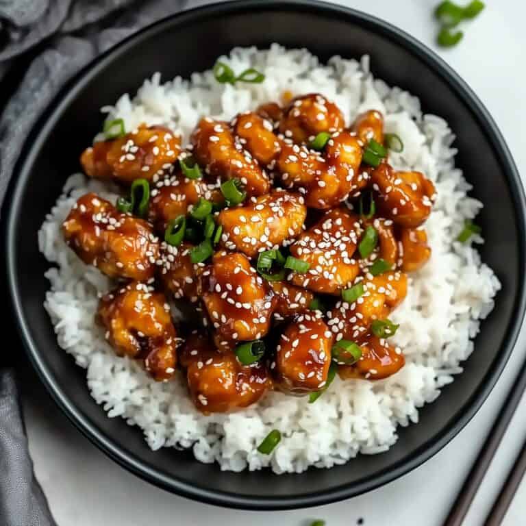 Flavor-packed sesame chicken served on fluffy white rice, garnished with green onions and sesame seeds. This easy Chinese cooking recipe is perfect for homemade Chinese food fans seeking classic Asian dishes.