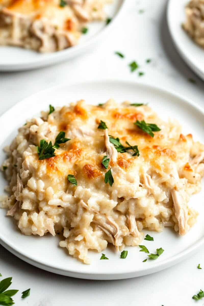 A close-up of creamy mushroom chicken and rice casserole served on a white plate, garnished with fresh parsley.