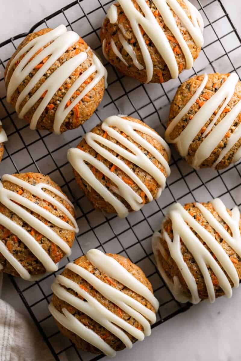 Carrot cake cookies with cream cheese glaze cooling on a wire rack.