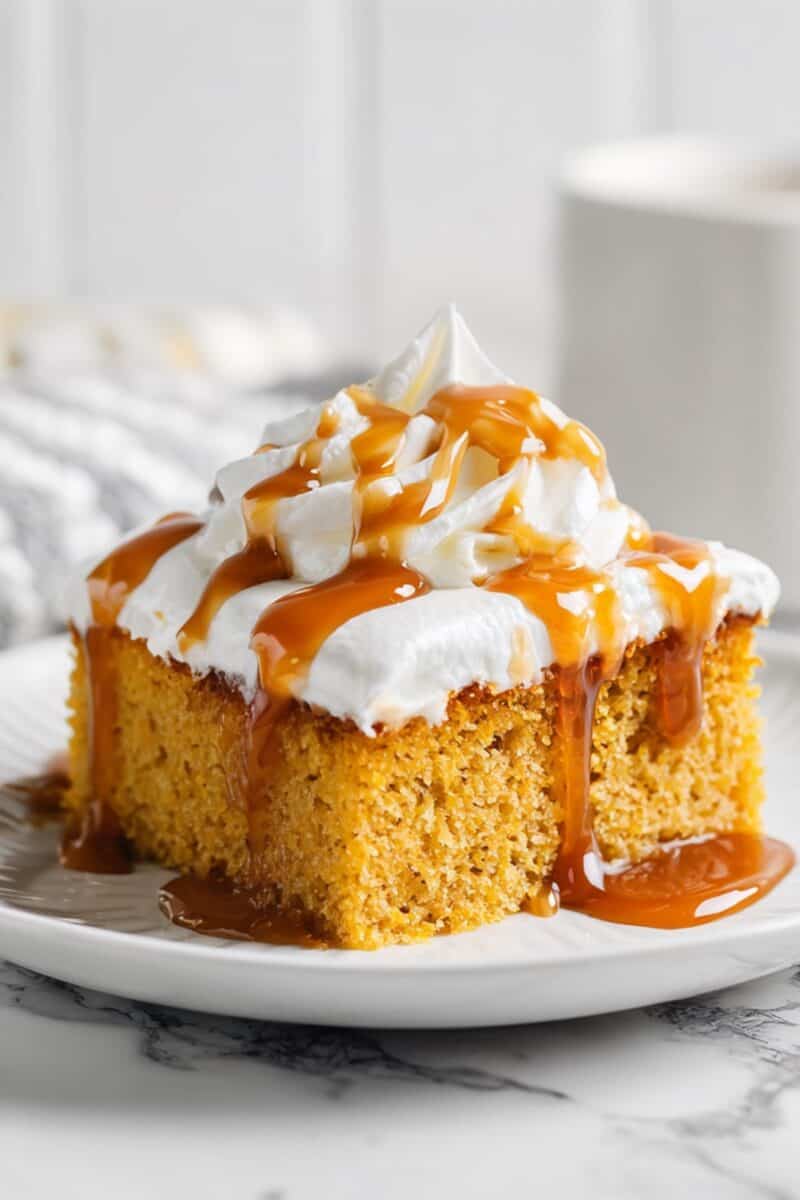 Close-up of a square slice of Pumpkin Tres Leches Cake, showing the soaked sponge layers, creamy topping, and rich caramel drizzle — an easy make-ahead fall treat.