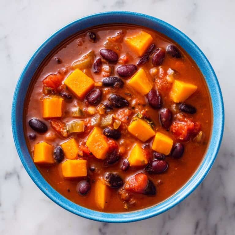 Overhead view of butternut squash chili with beans and tomatoes in a blue serving bowl.