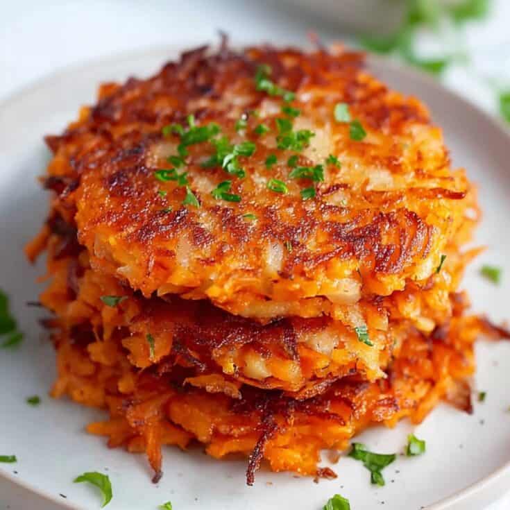 Stack of crispy golden sweet potato hash browns on a white plate, garnished with fresh parsley. Gluten-free vegetarian hash browns perfect for breakfast, brunch, or holiday side dishes.