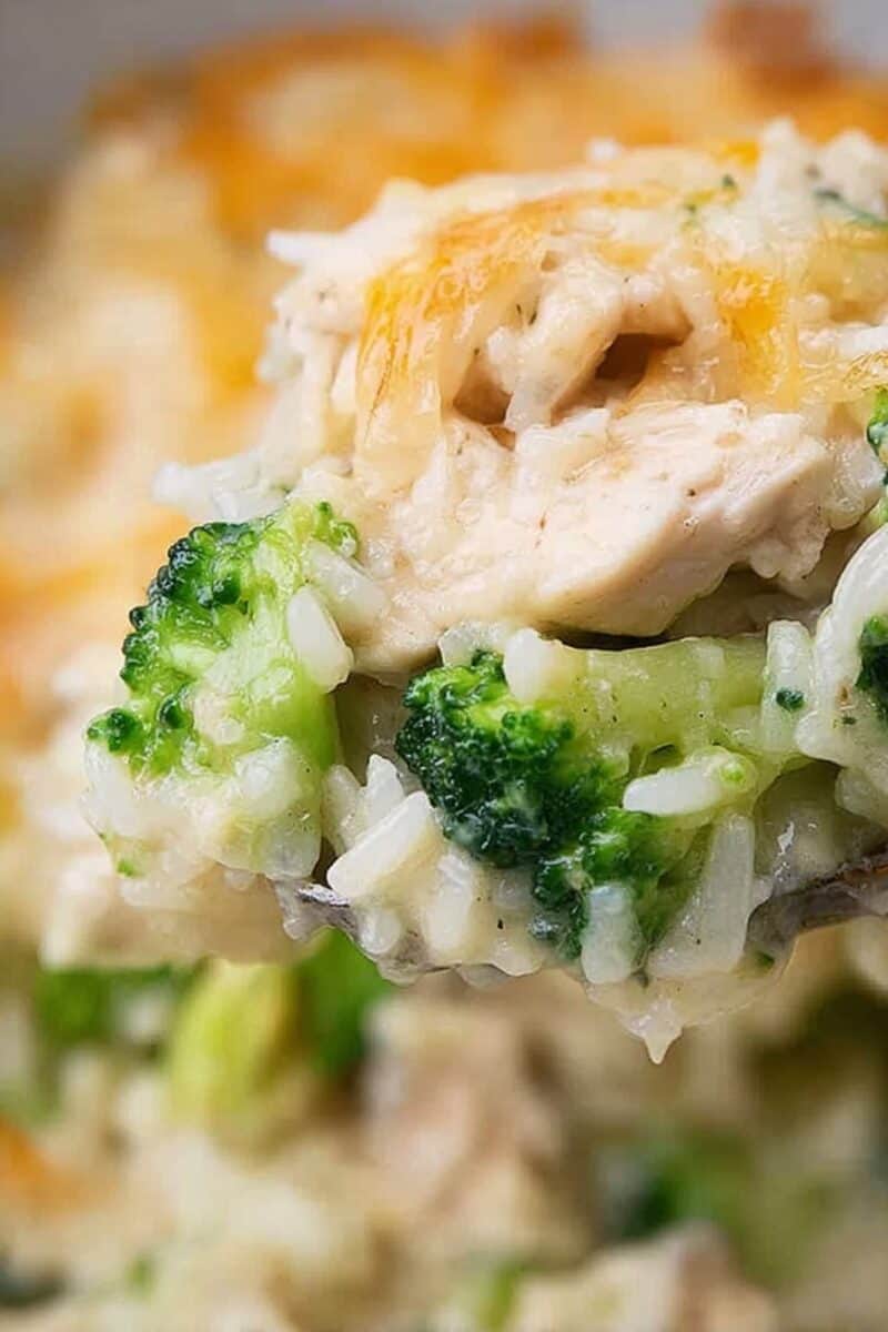 Close-up of creamy chicken broccoli rice bake showing fluffy rice, melted cheese, and bright green broccoli pieces.