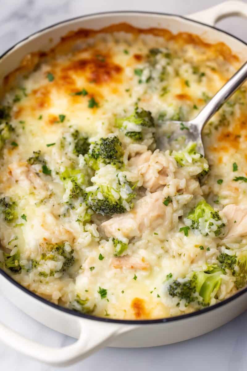 Top view of freshly baked chicken broccoli rice casserole in a white pan, golden and bubbling with melted cheese.