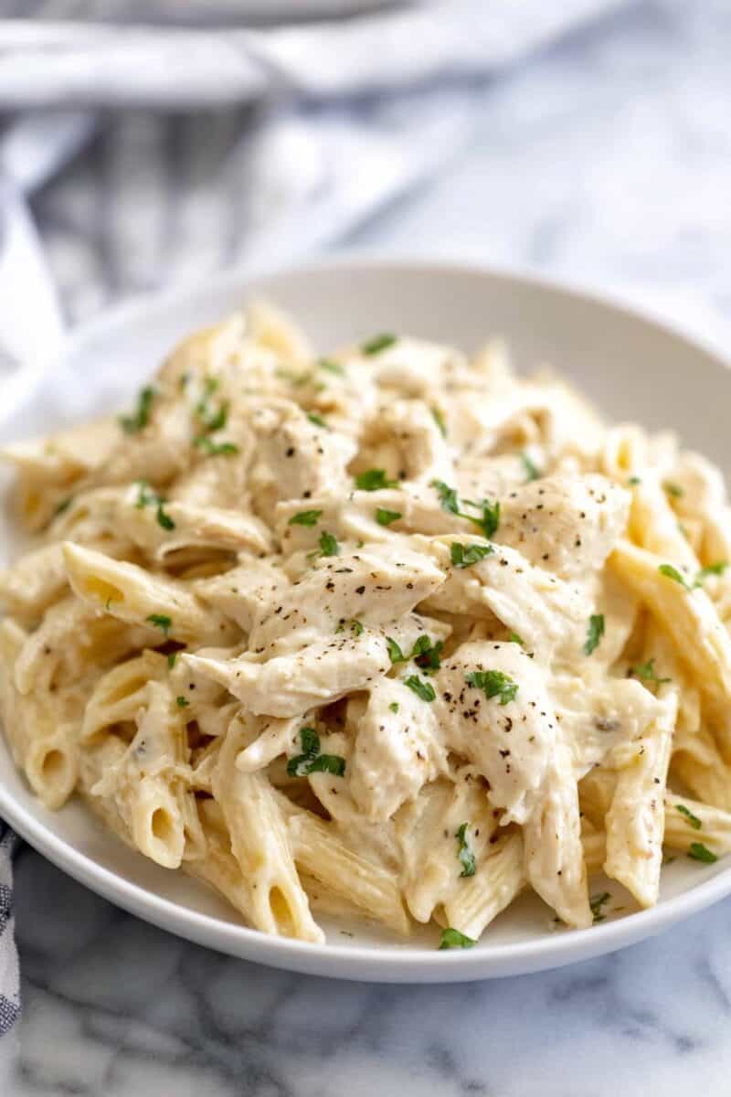 Creamy ranch chicken pasta with penne and shredded chicken in a rich sauce on a white plate.