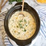 Creamy ranch chicken cooking in a slow cooker with shredded chicken and melted cheese in a rich sauce.
