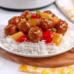 Crockpot sweet and sour chicken meatballs with pineapple and bell peppers served over white rice with glossy sauce