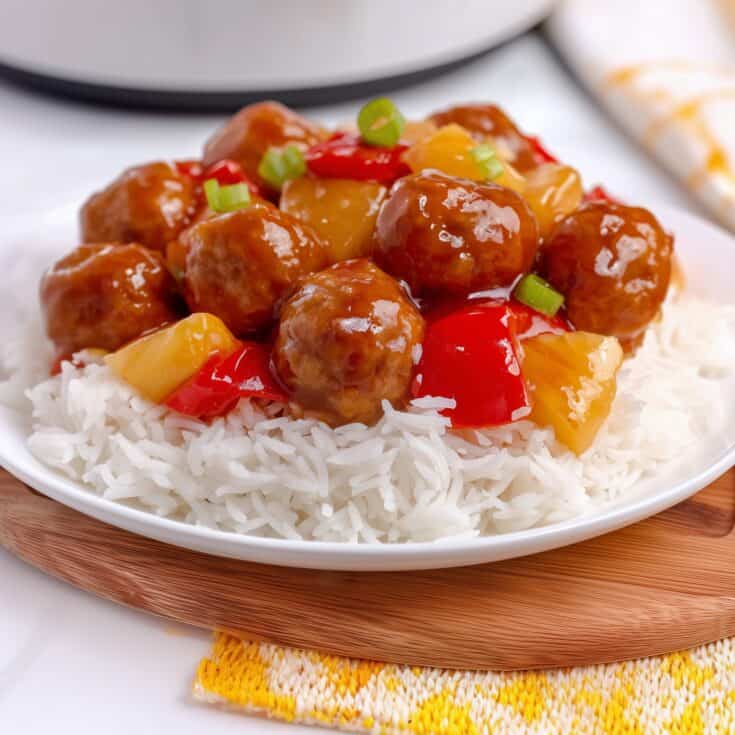 Crockpot sweet and sour chicken meatballs with pineapple and bell peppers served over white rice with glossy sauce